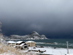白くなった猫崎半島と真っ黒な海上の雪雲